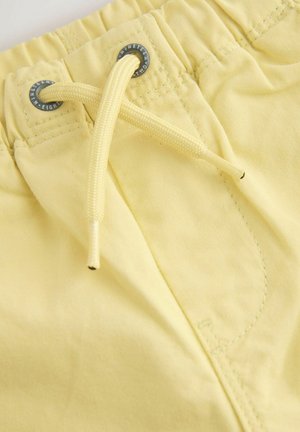 Pantaloni scurți din material galben, cu talie elastică, șnur ajustabil și detalii contrastante de cusături. Vedere de aproape care evidențiază texturile.