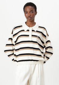 Stripet polo genser i beige, svart og brun nyanser. Har krage, tre knapper og en avslappet passform. Myk strikket tekstur.