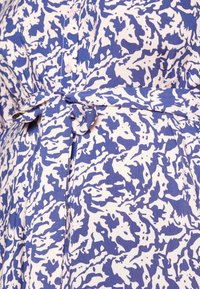 Modré a bílé vzorované tkaniny s detailem na šněrování, měkkou texturou a směsicí abstraktních tvarů z hladkého bavlněného materiálu.