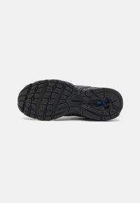 Semelle de chaussure de sport noire avec un motif en caoutchouc, présentant des rainures et des éléments de traction, conçue pour l'adhérence et la durabilité.