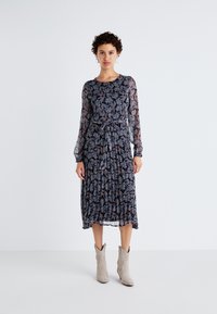 Φορεμα με μακριά μανίκια και σκούρα λουλούδια, που διαθέτει σφιχτή μέση, πλισέ φούστα και ημδιαφανή μανίκια. Συνδυάζεται με ανοιχτό γκρι μποτάκια έως τον αστράγαλο.