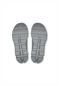 Semelles de chaussures de sport grises avec une surface en caoutchouc texturé, présentant divers motifs en grille et rainures pour une meilleure traction et stabilité.
