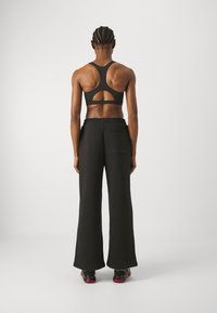 Svart sportbh med skuren rygg, kombinerad med löst sittande svarta byxor med bakfickor. Slät tygkvalitet, minimalistisk design.