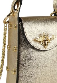 Metallische goldene Handtasche mit einem bienenförmigen Verschluss, strukturiertem Finish und goldenen Hardware-Akzenten sowie einer Kettenriemen.