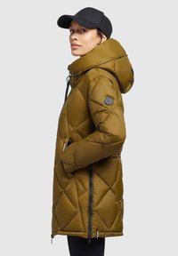 Olive green puffer coat with a hood, diamond quilted design, two side zippered pockets, and a black emblem on the sleeve.