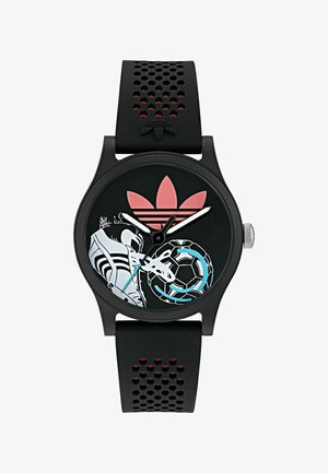 Čierne hodinky z silikónu s textúrovaným remienkom, vybavené okrúhlym čiernym ciferníkom, bielymi akcentmi a farebnými športovými grafikami, vrátane futbalovej lopty.
