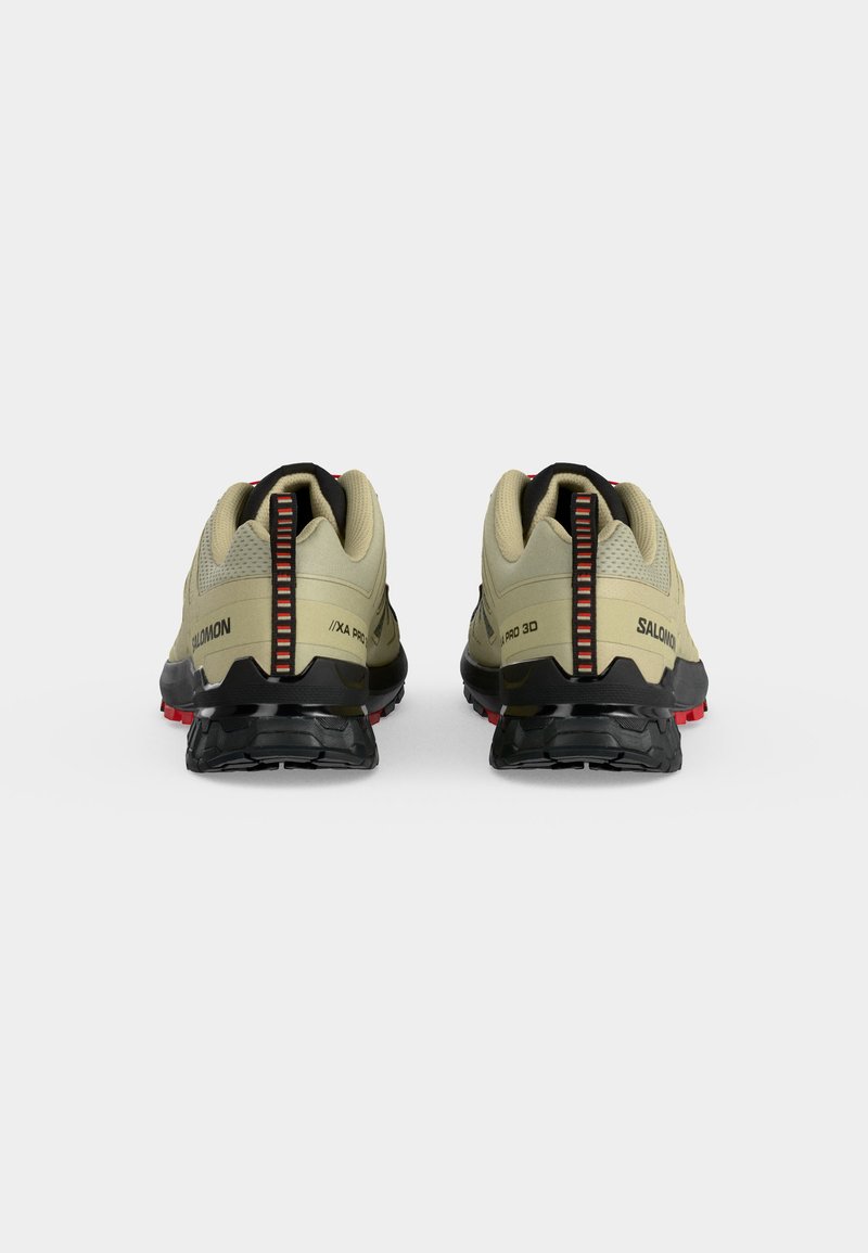 Paire de chaussures de trail beige Salomon vues de dos, avec semelles noires et languettes de talon accentuées en rouge.