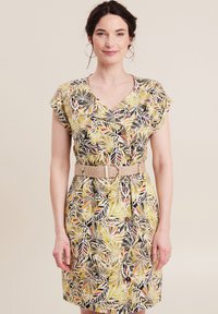 Bloemenjurk in geel, groen en zwart met korte mouwen, V-hals en knoopaccenten. Inclusief een textuurbeige gevlochten riem.
