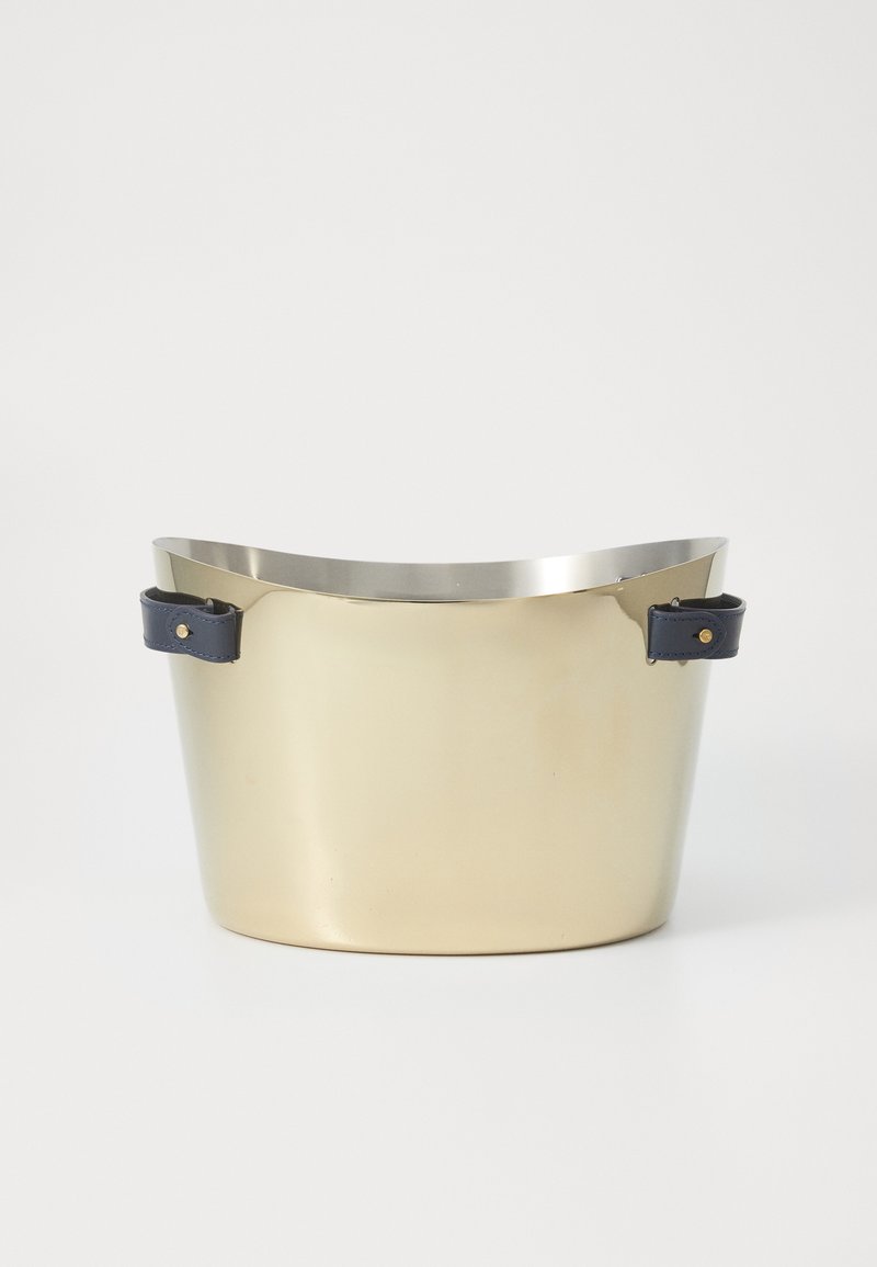 En mässingsfärgad metallhink med en slät yta, rundad topp och mörkblå läderhandtag med guldakzent.