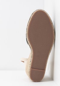 Semelle en espadrille, extérieur en jute naturel, couleur beige, base plate en caoutchouc avec motif texturé, taille 39 imprimée au fond.