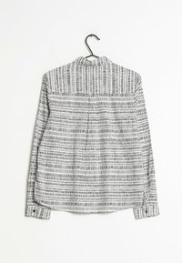 Camicia a maniche lunghe in bianco e nero con un design a motivo caratterizzato da linee orizzontali e verticali; tessuto leggero con colletto.