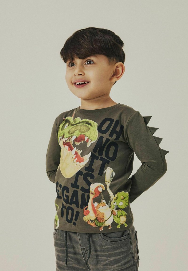 Langarm-Olivgrün T-Shirt mit einem Dinosaurier-Graphic und Text, ausgestattet mit strukturierten Spike-Details an den Schultern.
