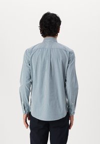 Camicia a quadri blu e bianca con colletto abbottonato, maniche lunghe e polsini. Realizzata in cotone, presenta una texture liscia e leggera.