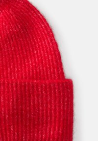 Rød strikket lue med vertikal ribbet tekstur. Myk ullblanding materiale. Oppbrettet bunndesign for ekstra varme.