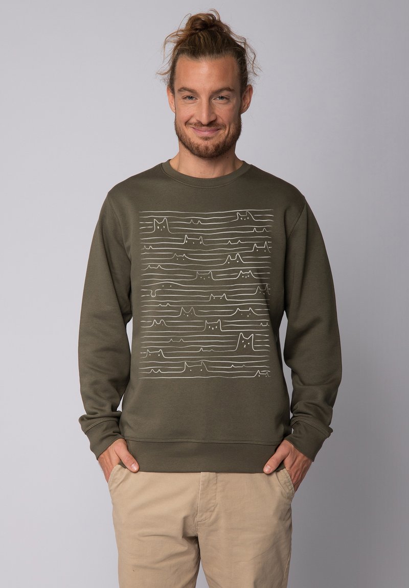 Olijfgroene sweatshirt met lange mouwen, voorzien van een wit golvend lijnpatroon dat lijkt op kattencontouren over de voorkant. Zachte textuur.