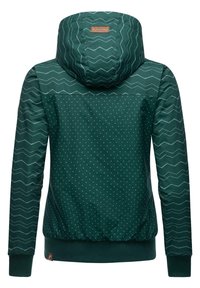 Veste verte avec capuche, présentant un motif en zigzag en haut et des pois en bas. Elle possède des poignets côtelés et une coupe ajustée à la taille.