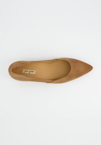 Chaussure plate en daim couleur tan, avec un bout pointu et des côtés échancrés. La semelle intérieure est de couleur beige clair avec le label de la marque visible.