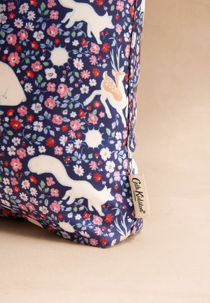 Mėlyna gėlių pagalvėlė su baltais gyvūnais, įskaitant lapiną ir elnią, su išskirtine Cath Kidston etikete vienoje pusėje.
