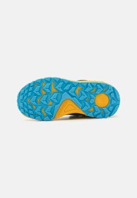 Semelle de chaussure noire avec une base en caoutchouc bleu texturé, présentant des accents jaunes et un motif de semelle robuste pour une adhérence sur diverses surfaces.