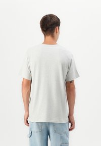 Light gray cotton t-shirt with short sleeves and a round neckline, featuring a relaxed fit. The back shows a simple, smooth design.