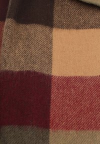 Wolblend stof met een ruitpatroon in donkerbruin, gedempt rood, beige en tan vierkanten. Zachte textuur met een lichte fuzzy uitstraling.