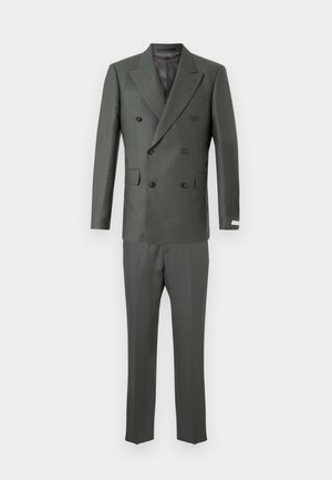 Sötétzöld, kétsoros zakó, álló hajtókákkal, két elülső zsebbel és egyenes szárú nadrággal. Texturált anyag, amely enyhe fényt tükröz.