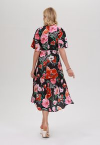 Florales Kleid mit kurzen schwingenden Ärmeln, schwarzem Hintergrund, großen pinken und roten Blumen, schichteter Rock und knöchellanges Design.