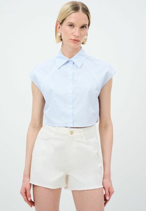 Lichtblauwe, korte mouwen, cropped button-up shirt met verticale strepen. Gepaard met witte denim shorts met een rafelrand.