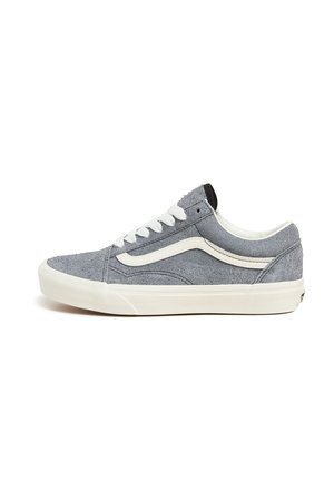 Zapatilla deportiva baja gris con franja lateral blanca, cordones blancos y suela gruesa blanca de goma sobre fondo blanco liso.