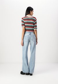 Striped crop top in red, green, and blue with short sleeves; paired with light blue wide-leg jeans and black platform shoes.
