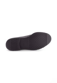 Zwarte rubberen zool met een gestructureerd grippatroon, voorzien van een gladde afwerking en een ronde teen. Logo ingedrukt op het hielgebied.