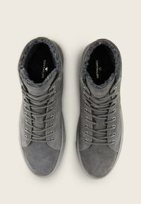 Zapatillas altas de ante gris con un suave forro de piel, que cuentan con ojales metálicos, cordones y una suela de goma. Marca visible en el interior.