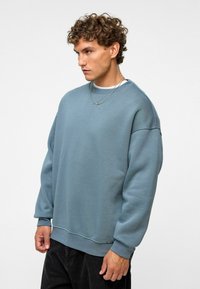 Lichtblauwe oversized sweatshirt van zachte stof, met een ronde hals, geribbelde manchetten en een rechte zoom met minimale details.