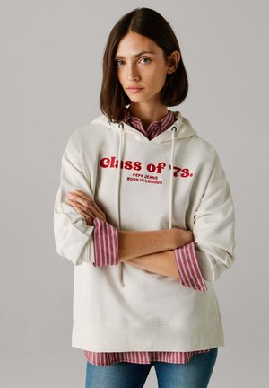 Crèmewitte hoodie met de tekst "class of '73" in het rood gedrukt, uitgevoerd met een capuchon met trekkoord en lange mouwen over een rood-wit gestreept shirt.