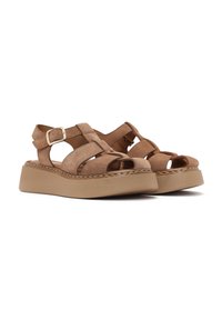 Sandali con zeppa in suede marrone, cinturini incrociati e fibbia alla caviglia regolabile. Presentano una suola spessa di un marrone chiaro e un design aperto sulla punta.