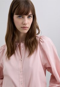 Lichtroze blouse van katoen met een losse pasvorm, voorzien van pofmouwen, een knoopsluiting aan de voorkant en kleine, ronde knoopjes.