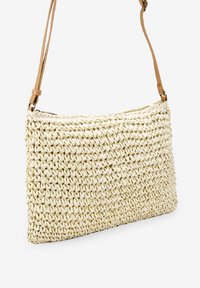 Borsa in paglia intrecciata di forma rettangolare, colore beige, con una tracolla in pelle. Presenta una superficie testurizzata e una chiusura a zip.
