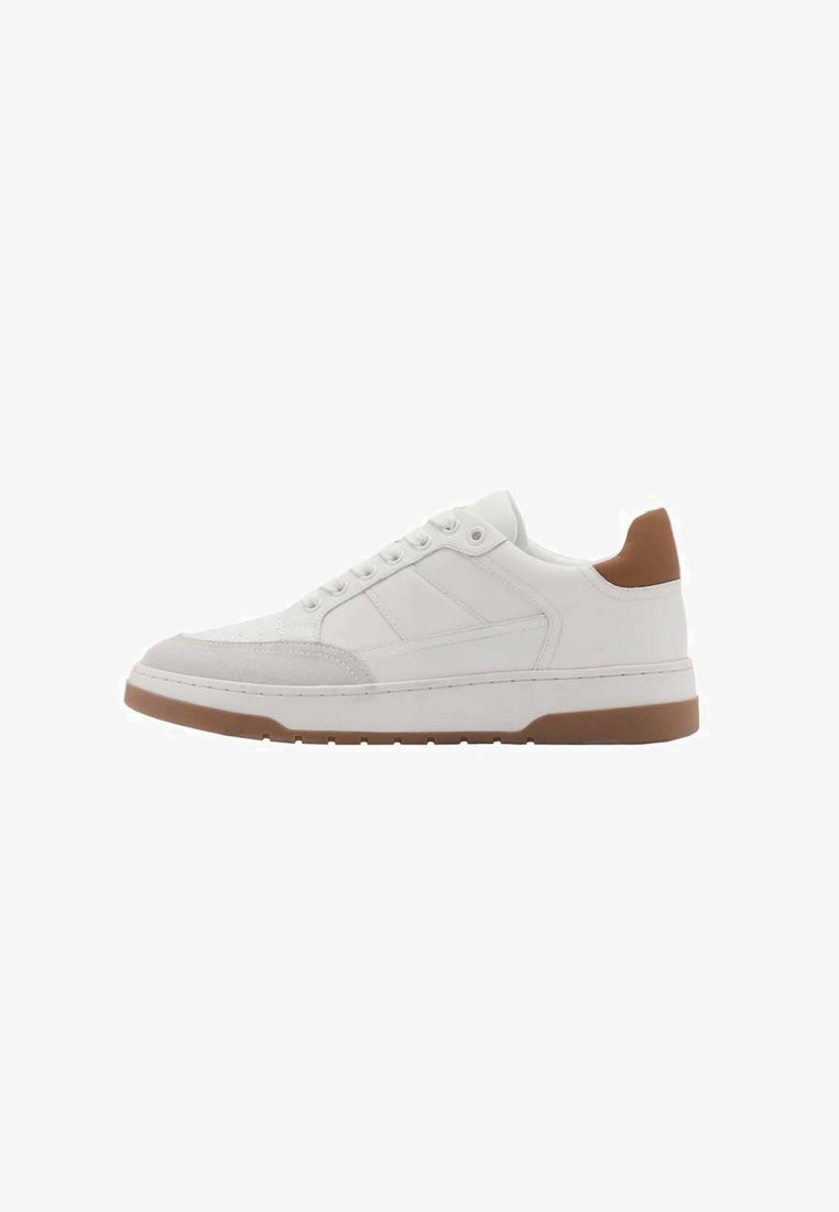 Tenis alb cu accente din velur și piele, având o talpă din cauciuc și un detaliu de călcâi maro. Design cu sireturi și cusături vizibile.