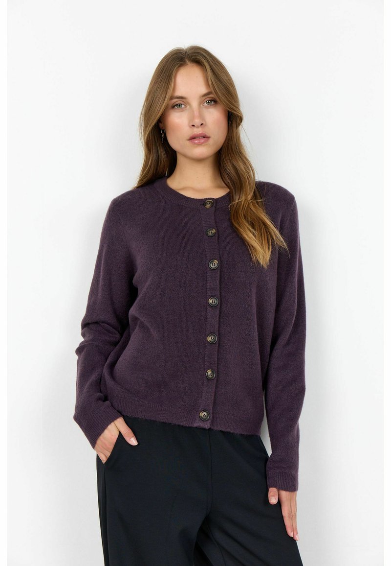 Cardigan violet cu guler rotund, mâneci lungi și închidere cu butoane, realizat dintr-un material moale; are butoane mari de culoare închisă și o croială lejeră.