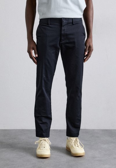 Marineblauwe broeken van katoen, met een rechte pasvorm, twee voorzakken en een minimalistische constructie. Gedragen met lichte sneakers.