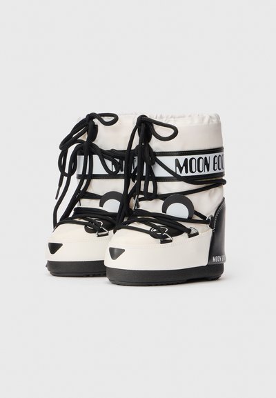 Witte en zwarte hoge Moon Boot sneeuwlaarzen met zwarte veters en logo op de zijkant, van de voorkant weergegeven op een effen achtergrond.