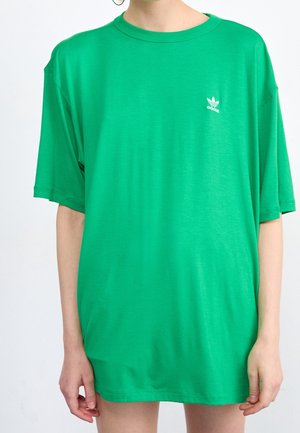 Grünes, übergroßes T-Shirt mit kurzen Ärmeln aus weichem Stoff; verfügt über ein kleines weißes Adidas-Logo auf der linken Brustseite.