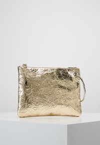 Złota metaliczna kopertówka wykonana z pomarszczonego materiału, z zamknięciem na zamek błyskawiczny i okrągłym uchwytem. Prostokątny kształt o gładkiej fakturze.