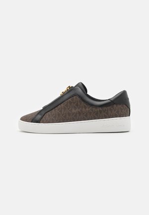 Sneaker slip-on marrone con motivo, dettagli in pelle nera e suola bianca, caratterizzato da una zip decorativa.