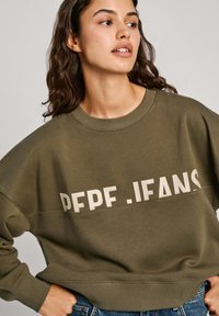 Sudadera verde oliva con un corte relajado, que presenta un logo horizontal "PEPE JEANS" en color crema. Fabricada con un tejido suave y con puños de canalé.