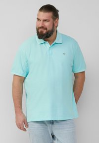 Lichtblauwe poloshirt gemaakt van zachte stof, met een klassieke kraag en korte mouwen. Klein logo op de borst. Gerged met lichtdenim jeans.