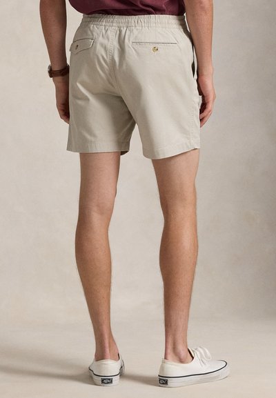 Beige bomullsshorts med resår i midjan, två bakfickor med knappstängning och en ren, avslappnad design.
