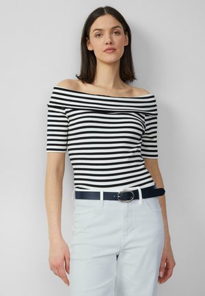 Zwart-wit gestreepte off-the-shoulder top met korte mouwen, gecombineerd met lichtblauwe hoge taillebroeken en een marineblauw riem.