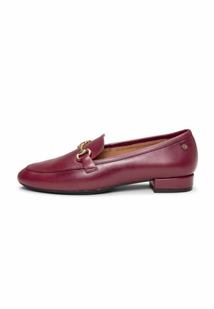 Mocasín de cuero burdeos con tacón bajo y detalle metálico dorado en forma de estribo sobre la parte superior, forro interior acolchado de color beige y suela negra.