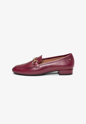 Mocasín de cuero burdeos con tacón bajo y detalle metálico dorado en forma de estribo sobre la parte superior, forro interior acolchado de color beige y suela negra.